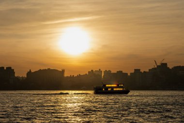 Manhattan silueti üzerinde canlı bir gün doğumu Hudson Nehri boyunca Hoboken, NJ 'den izleniyor, parlayan bulutları yakalıyor ve sabahın erken saatlerinde suya yansıyan ışığı yansıtıyor..