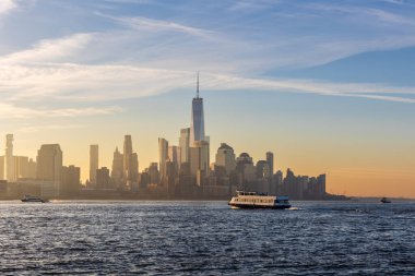 Manhattan silueti üzerinde canlı bir gün doğumu Hudson Nehri boyunca Hoboken, NJ 'den izleniyor, parlayan bulutları yakalıyor ve sabahın erken saatlerinde suya yansıyan ışığı yansıtıyor..