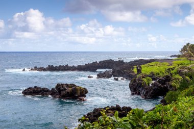 Maui 'deki Waianapanapa Eyalet Parkı' nın engebeli volkanik kıyı şeridi derin mavi suları ve okyanus tarafından şekillendirilmiş dramatik lav kayalıklarıyla. Hana, Hawaii 'den.