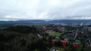 Isla Teja üzerinde panoramik bir hava manzarası, ada yerleşim alanları, parklar ve çevresindeki yemyeşil ormanların bir kombinasyonunu gösteriyor. Uzakta, Valdivia şehri yavaş yavaş...