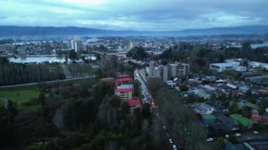 Şili 'nin Valdivia kentini Isla Teja perspektifinden yansıtan atmosferik hava manzarası. Görüntülerde modern Pedro de Valdivia oteli ön planda yer alırken, şehir merkezi