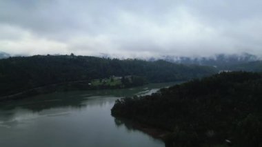 Şili Valdivia 'nın doğal güzelliğini gösteren sinematik bir çekim. Görüntüler, yemyeşil bir tepenin etrafını saran sakin bir nehri yavaş yavaş ortaya çıkaran bir dron kaldırmasıyla başlıyor. Şey...