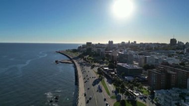 Güneş batarken Montevideo kıyı şeridinin çarpıcı hava manzarası şehrin her tarafına uzun gölgeler düşürüyor ve suları aydınlatıyor. Çekim, şehir ve sahil yaşamının eşsiz bir karışımını yakalıyor.