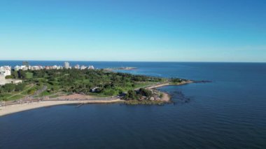 Açık ve güneşli bir günde Montevideo kıyı şeridinin nefes kesici panoramik manzarası. Görüntü, Rambla 'nın şehir plajları boyunca uzanan, yemyeşil alanlar, el değmemiş sular ve