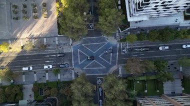 Dikey bir hava görüntüsü, yukarıdan görüldüğü gibi eşsiz, geometrik desenli bir şehir kavşağını yakalıyor. Sahne, yolların, yaya geçitlerinin ve bisiklet yollarının ayrıntılı planlarını vurguluyor.