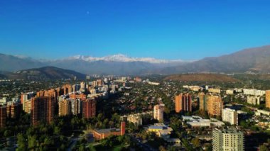 Göz kamaştırıcı bir panoramik hava manzarası çarpıcı bir dağ zeminiyle canlı bir şehir yakalıyor. Görüntü, şehir hayatı ile görkemli karlarla kaplı dağlar arasındaki zıtlığı gösteriyor.