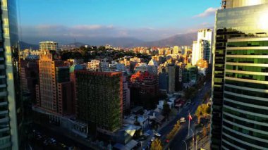 Santiago Şili 'nin insansız hava aracı görüntüleri günbatımında modern gökdelenleri, konut binalarını ve And Dağları' nı gösteriyor. Video, mimari ve kentsel yoğunluğun karışımını yakalıyor.