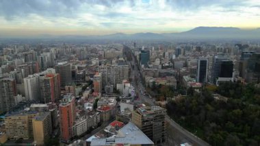 Santiago Şili 'nin geniş hava manzarası yukarıdan çekildi. Yoğun şehir manzarası ufka doğru uzanan uzun bir merkez bulvarla birlikte uzaklığa kadar uzanır. Modern ve tarihi