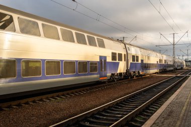 İki katlı görkemli bir yüksek hızlı tren günbatımının arkaplanına karşı modern köprüden hızla geçiyor.