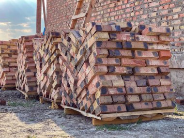 Fotoğraf üst üste dizilmiş bir küp kırmızı tuğlayı gösteriyor. Güçlü ve istikrarlı bir yapı oluşturuyor..