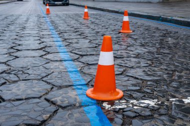 Parlak turuncu yol konileri, kentte tamirat devam ederken araçlara güvenli bir şekilde rehberlik etmek için asfalt bir yolda konumlandırıldı.