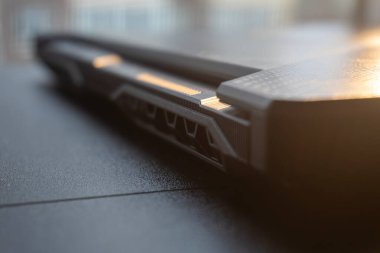 Öğleden sonra ışığı altında parlak bir kapalı alanda bir oyun dizüstü bilgisayarının tasarımı ve özelliklerini vurgulayan detaylı bir yakın plan.