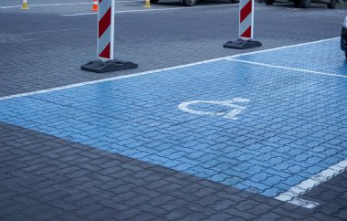Engelliler için bir park yeri, kaldırım taşları maviye boyanmış ve ortada bir tabela var.