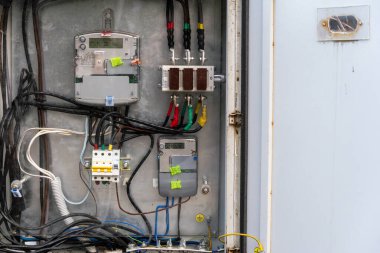 Elektrik kontrol panelinin detaylı bir görüntüsü bir kullanım ortamında metre, kablo ve renkli bağlantıları gösterir