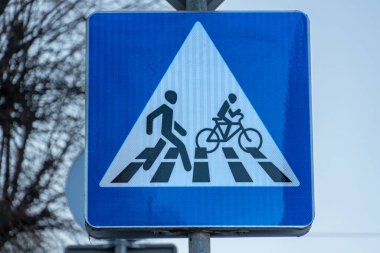 Mavi üçgen bir levhada bir yaya ve bisikletçinin figürleri gösteriliyor. Bu da her ikisi için de şehir ortamında belirlenmiş bir sınır kapısı anlamına geliyor.