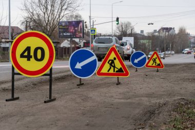 Parlak renkli trafik işaretleri, şehir ortamında sürmekte olan yol çalışmaları arasında bir hız limitini ve doğrudan sürücüleri gösteriyor