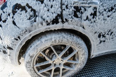 Araba tekerleği oto yıkamada, direksiyona köpük sürülüyor.