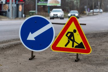 Trafik işaretleri yol yapımına işaret ediyor. Bulutlu bir günde şehir kavşağında şoförlere rehberlik ediyor.