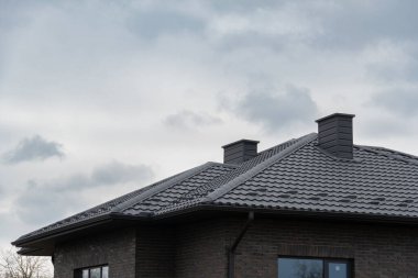 Metal kaplı bir çatıdaki iki baca Bulutlu bir günde