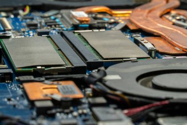 Bir bilgisayar anakartının detaylı incelemesi gösteriyor ki bellek modülleri, bakır ısı boruları ve çeşitli elektronik bileşenler cihazın içinde karmaşık bir şekilde düzenlenmiş.