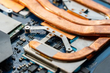 Bakır ısı boruları, bir teknoloji üretim alanında bulunan bir anakart üzerindeki çeşitli elektronik parçaların etrafına sarılmış durumda. Karmaşık tasarım ısı kaybına yardımcı oluyor.