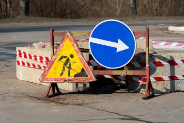 İnşaat işaretleri boş bir şehir merkezinde kavşağın yakınına konmuş, trafiği yönlendiriyor ve bölgede devam eden işler hakkında bilgilendirme yapıyor.
