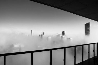 This image captures a striking black and white photo depicting a mysterious city shrouded in dense fog, creating an atmospheric scene clipart