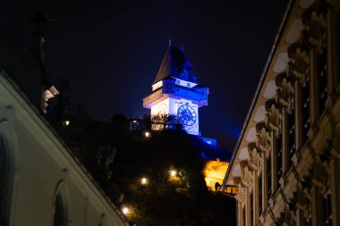 Geceleri, muhteşem bir saat kulesi çarpıcı mavi ışıklarla aydınlanır ve karanlık gökyüzüne karşı çarpıcı bir görüntü oluşturur.