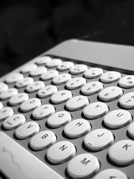 Yuvarlak tuşlu siyah beyaz bir klavyenin yakın çekimi. Anahtarlar standart QWERTY düzeninde düzenlenmiştir. 