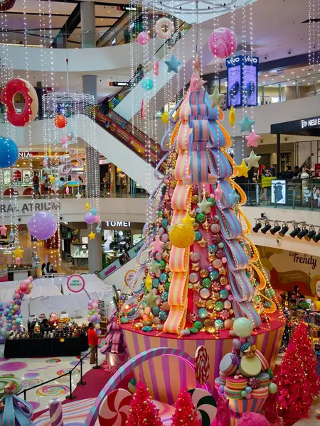 Tatiller için dekore edilmiş parlak, şenlikli ve kaprisli bir alışveriş merkezi, muhtemelen Noel, merkezinde büyük, renkli, şeker temalı bir sergi..