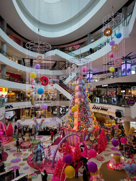 Tatiller için dekore edilmiş parlak, şenlikli ve kaprisli bir alışveriş merkezi, muhtemelen Noel, merkezinde büyük, renkli, şeker temalı bir sergi..