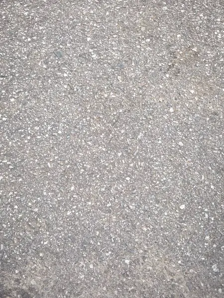 Gri asfalt bir yüzeyin kabataslak bir dokusu olan yakın çekim, yukarıdan aşağı bir görüntüsü..