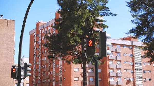 Kırmızılı yaya trafik lambası arkasında binalar olan bir şehirde.