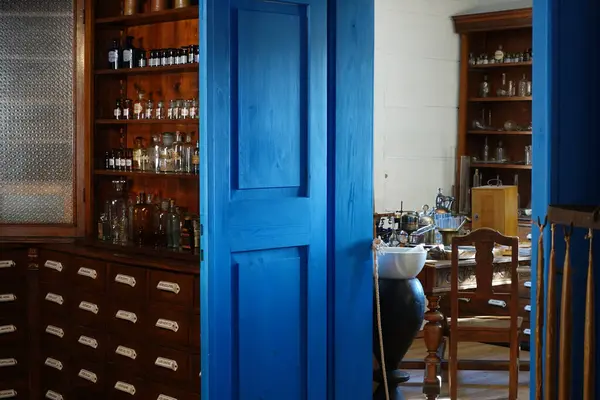 Ahşap dolapları, cam şişeleri ve klasik dekoru olan eski bir eczacının içinde tarihi bir tıbbi atmosfer yaratıyor..