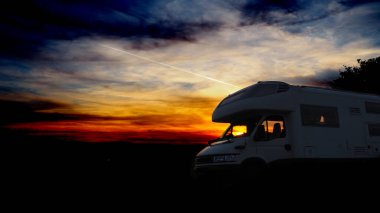 Gün batımının altında parketmiş bir karavan.