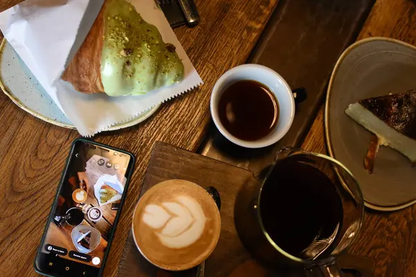 İçinde sanat olan bir latte, bir çaydanlık kahve, tereyağlı kruvasan ve cheesecake bulunan nefis bir kafe. Kahve molası için son derece rahat ve davetkar bir ortam..