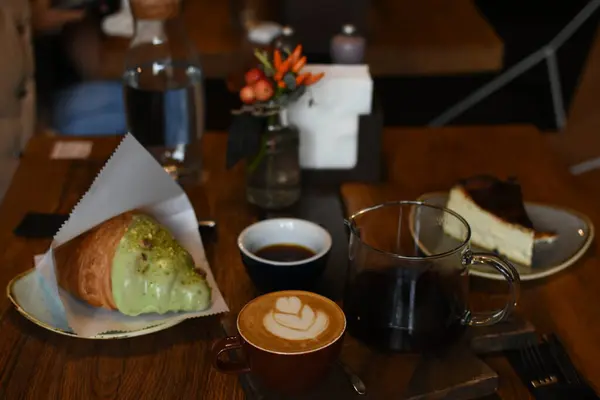 İçinde sanat olan bir latte, bir çaydanlık kahve, tereyağlı kruvasan ve cheesecake bulunan nefis bir kafe. Kahve molası için son derece rahat ve davetkar bir ortam..