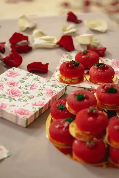 Tabak ve tepside sergilenen küçük, yuvarlak, kırmızı hamur işleri. Canlı renkleri ve hassas ayrıntıları görsel olarak çekici ve davetkar bir tatlı sunumu yaratır..