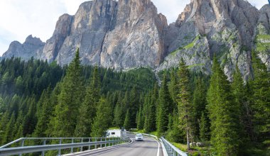 Arka planda kayalık bir dağ olan virajlı bir yol, Dolomitler, İtalya
