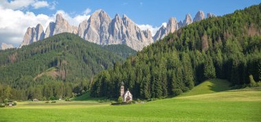 Yazın St. John Kilisesi 'nin arka planında sallantılı bir dağ olan Dolomitler, İtalya