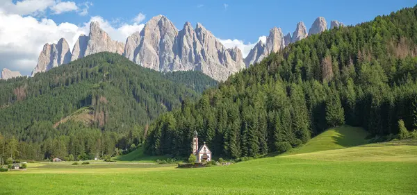 Yazın St. John Kilisesi 'nin arka planında sallantılı bir dağ olan Dolomitler, İtalya