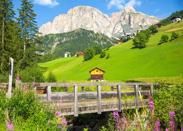Alp köyü ile ahşap bir köprü ve arka planda kayalık bir dağ, yaz, Dolomitler, İtalya