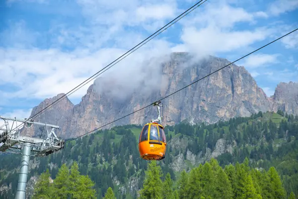 Dolomitler, İtalyan---27 Temmuz 2024: Corvara yakınlarında havada asılı duran turuncu renkli bir Colfosco teleferiği