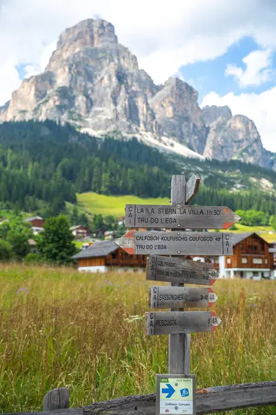 Dolomitler, İtalya 'da, tepenin aşağısında dağlık bir dağ köyü olan kayalık bir dağ yolu tabelası.