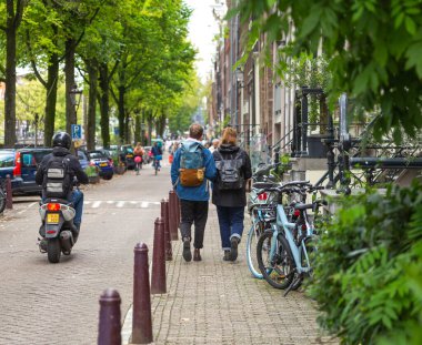 Amsterdam, Hollanda-22 Eylül 2023: Eski şehir caddesinde seyahat çantalı genç bir çift yürüyor