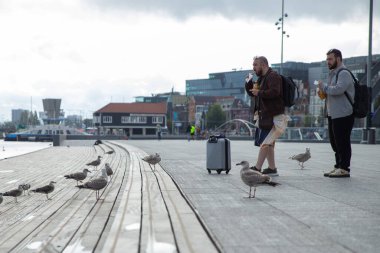 Amsterdam, Netherlands-Sep 22, 2023: Tourists feeding pigeons at the Amsterdam Central station water plein