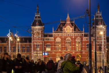 Amsterdam, Netherlands-Mar 29, 2024: the Amsterdam central station building and cruise at night clipart