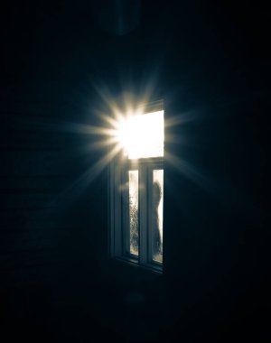 Gizemli ışığı olan eski, donmuş bir pencere. Camda buz var. Kış.