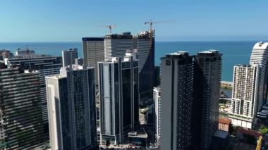 Büyük şehir, bir sürü gökdelen, denize bakan inşaat vinçleri.