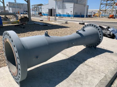 A large industrial Venturi flow meter on an industrial facility. The structure is painted gray and features flanged ends with bolt holes for connection to a larger piping system.  clipart